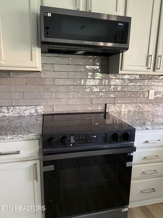 kitchen with stainless steel microwave, black range with electric cooktop, and decorative backsplash