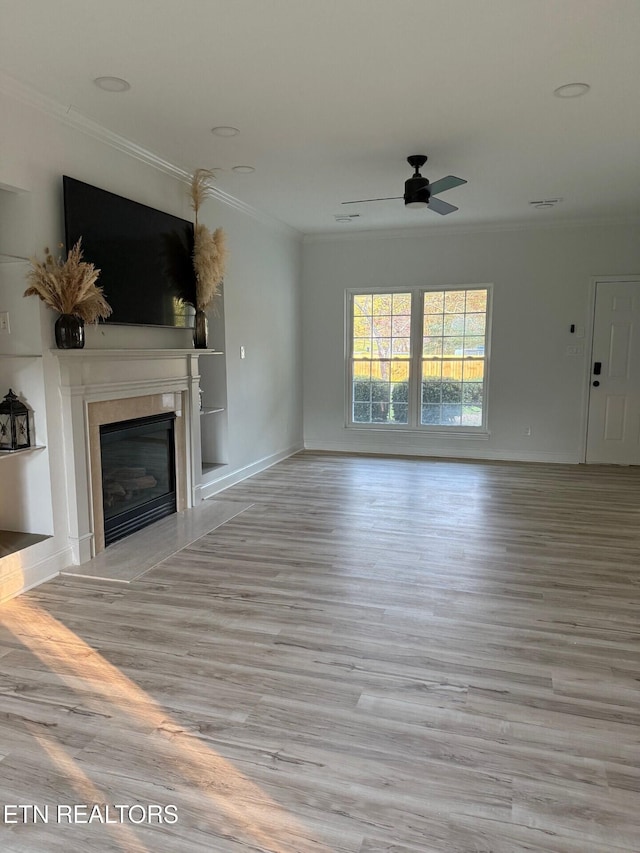 unfurnished living room featuring a glass covered fireplace, baseboards, crown molding, ceiling fan, and wood finished floors