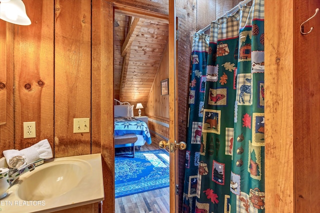 2580 Black Bear Ln, Sevierville, TN 37876 - ensuite bathroom featuring wood walls, vaulted ceiling, wood finished floors, vanity, and a shower with shower curtain