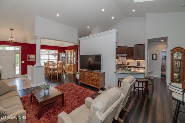 169 Dudi Trl, Vonore, TN 37885 - living area with wood finished floors, baseboards, decorative columns, high vaulted ceiling, and a notable chandelier