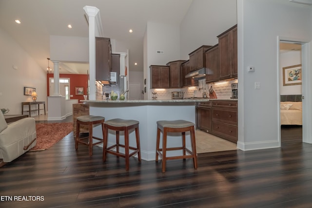 169 Dudi Trl, Vonore, TN 37885 - kitchen with a kitchen breakfast bar, dark wood-style floors, tasteful backsplash, dark brown cabinetry, and under cabinet range hood