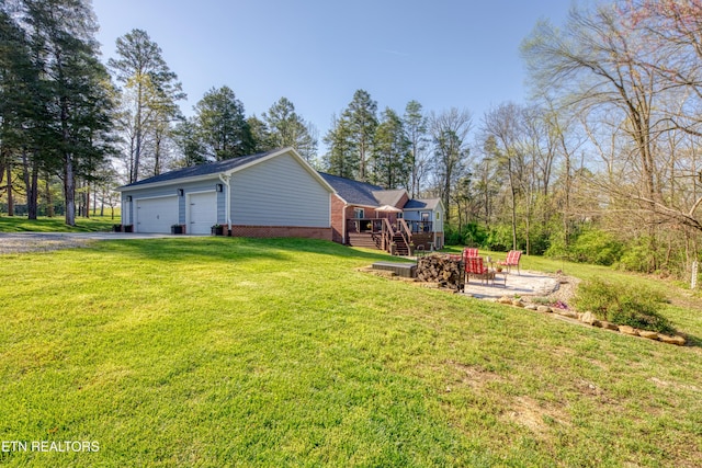 view of yard with a garage, an outdoor fire pit, a patio area, driveway, and a deck