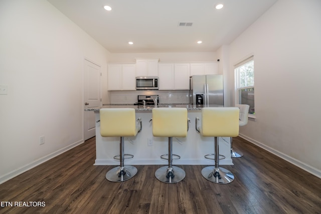 2740 Red Barn Rd, Knoxville, TN 37931 - kitchen featuring an island with sink, dark wood-type flooring, white cabinets, appliances with stainless steel finishes, and backsplash