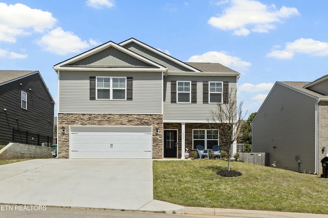craftsman-style home featuring a front yard, driveway, stone siding, and an attached garage