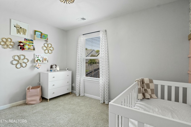 carpeted bedroom featuring a crib, baseboards, and visible vents