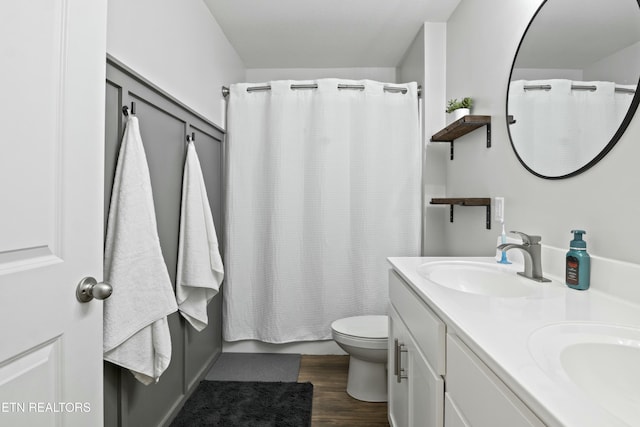 full bath featuring double vanity, wood finished floors, toilet, and a sink