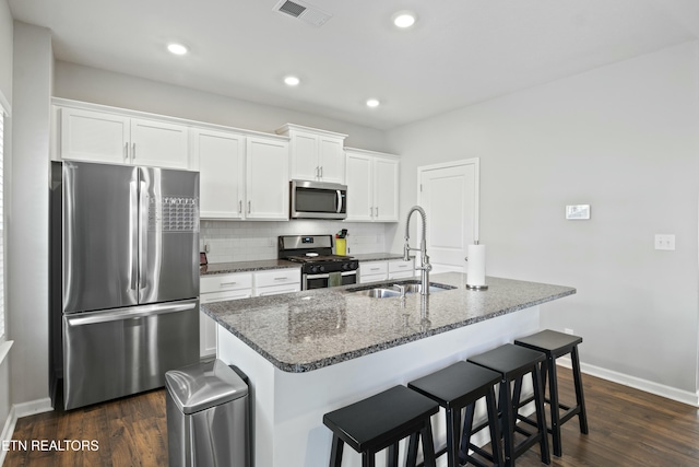 kitchen featuring appliances with stainless steel finishes, white cabinetry, visible vents, decorative backsplash, and a sink