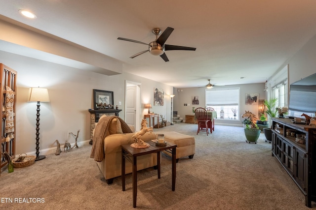 living room featuring carpet, baseboards, and ceiling fan