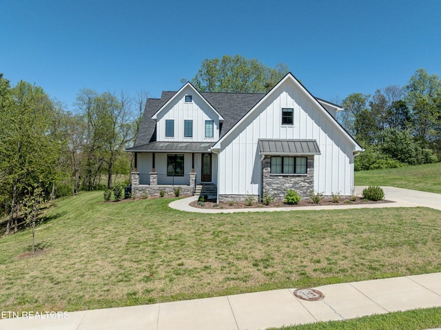 modern farmhouse with a standing seam roof, a porch, board and batten siding, and a front lawn