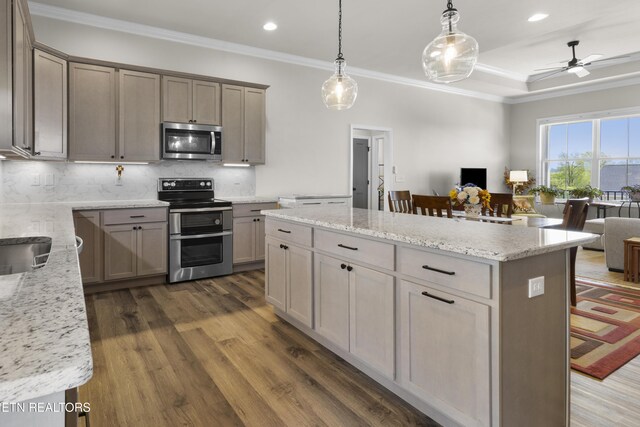 2718 Vista Meadows Ln, Sevierville, TN 37876 - kitchen featuring appliances with stainless steel finishes, open floor plan, decorative backsplash, wood finished floors, and a kitchen island