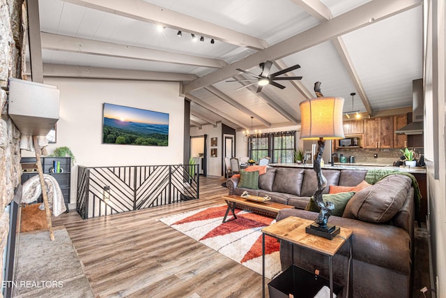 living area with lofted ceiling with beams, ceiling fan, and light wood-type flooring