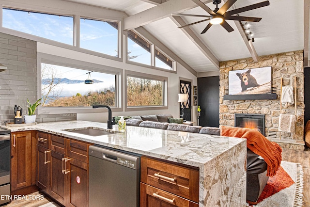 kitchen with dishwasher, a ceiling fan, a sink, a fireplace, and light wood-style flooring