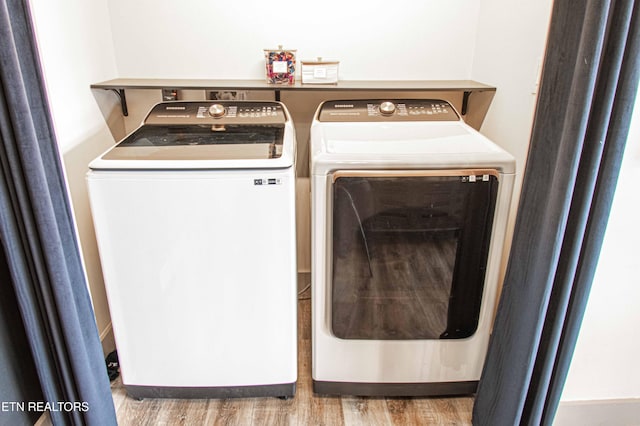 laundry area featuring wood finished floors, washer and clothes dryer, and laundry area