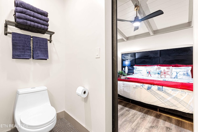 bathroom featuring beamed ceiling, wood finished floors, toilet, and a ceiling fan