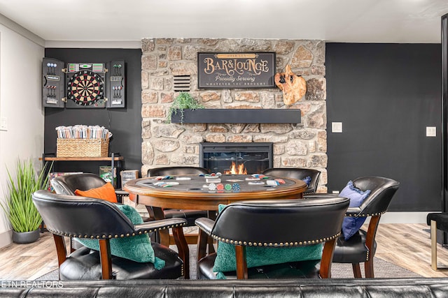 dining area featuring a stone fireplace and wood finished floors