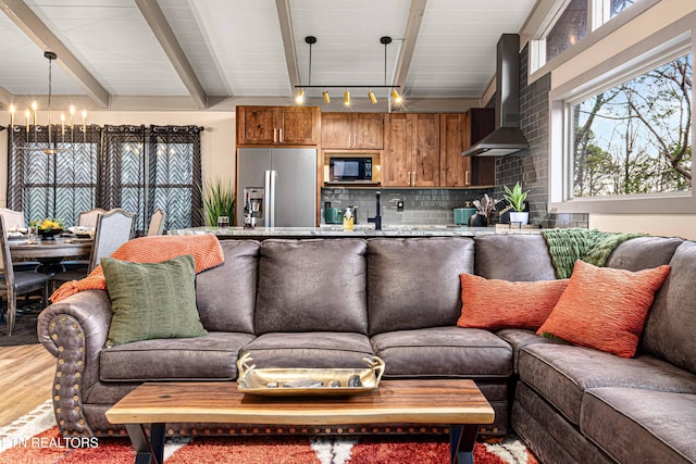 living area with light wood-style floors, beam ceiling, and a chandelier