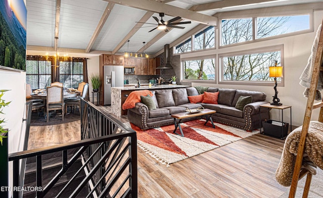 living room with high vaulted ceiling, ceiling fan with notable chandelier, beamed ceiling, and light wood-style flooring