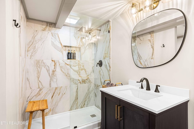full bath with a marble finish shower and vanity