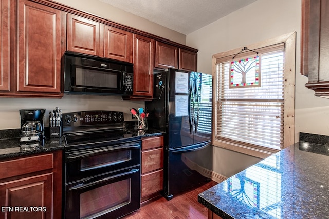 kitchen with baseboards, dark stone countertops, black appliances, and dark wood-style floors