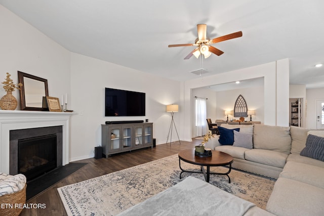 living room featuring a fireplace, ceiling fan, visible vents, and wood finished floors