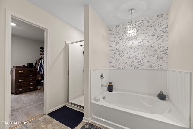 full bathroom featuring a shower stall, a spacious closet, a bath, and wallpapered walls