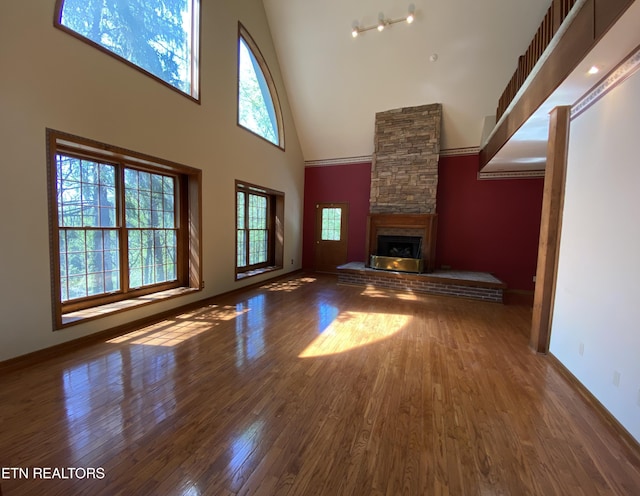 118 Mohawk Rd, Oak Ridge, TN 37830 - unfurnished living room featuring a towering ceiling, a stone fireplace, baseboards, and wood finished floors