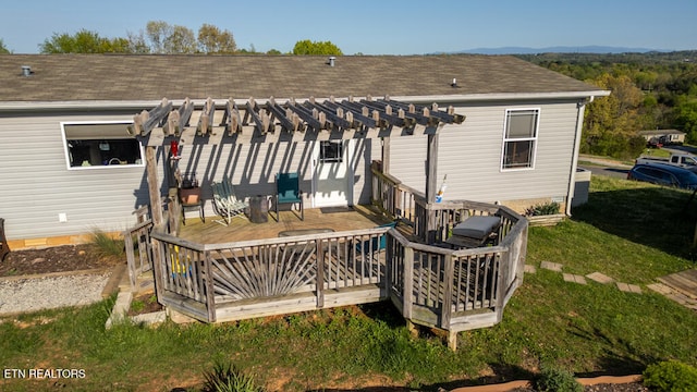 rear view of property featuring roof with shingles, a yard, a pergola, and a wooden deck