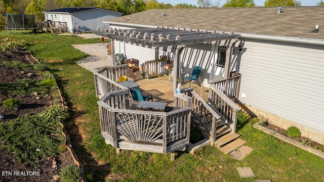 wooden terrace featuring a trampoline, a pergola, and a lawn