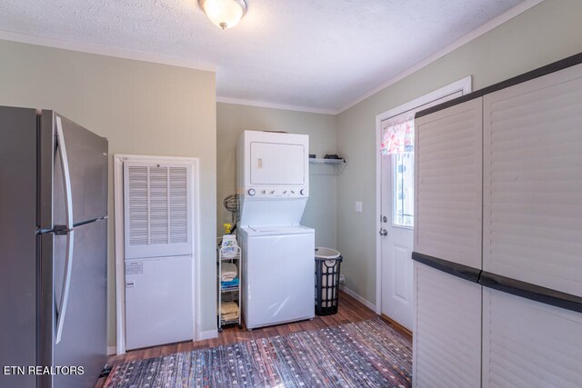 laundry room with baseboards, stacked washer and dryer, ornamental molding, laundry area, and wood finished floors