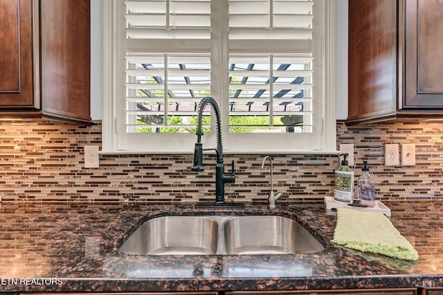 room details featuring dark stone counters, a sink, backsplash, and dark brown cabinets