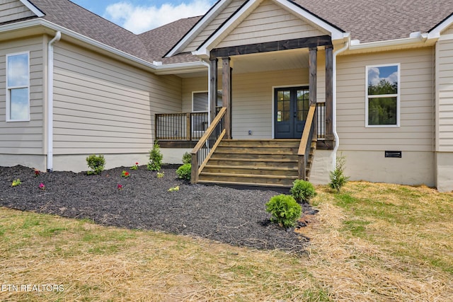 view of exterior entry featuring covered porch, french doors, and a shingled roof