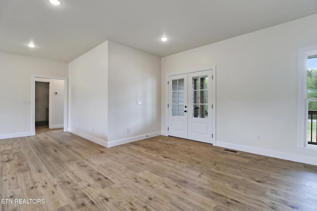 spare room featuring baseboards and light wood finished floors