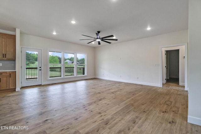 unfurnished living room with a ceiling fan, baseboards, recessed lighting, and light wood-style floors