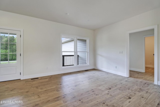 spare room featuring light wood-style floors, baseboards, and visible vents