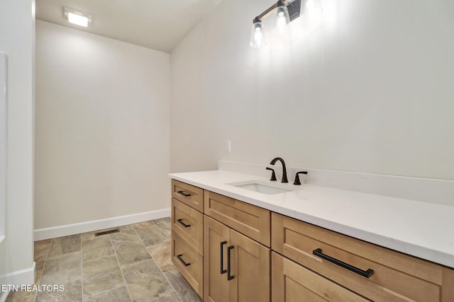 bathroom featuring baseboards, stone finish flooring, visible vents, and vanity