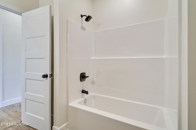 bathroom with baseboards, shower / tub combination, and wood finished floors