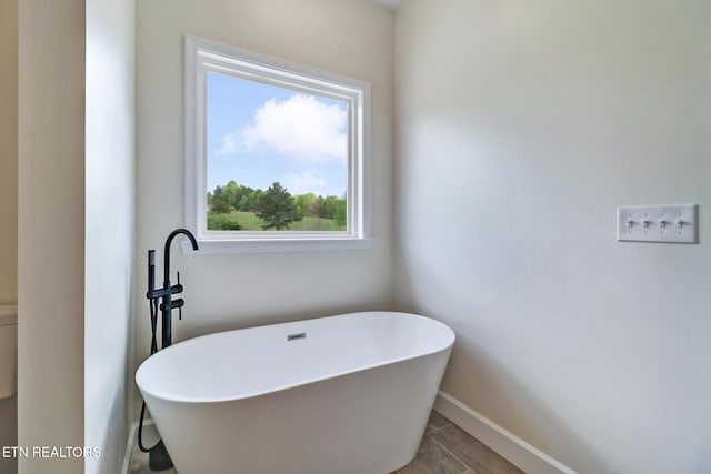 bathroom featuring baseboards and a soaking tub
