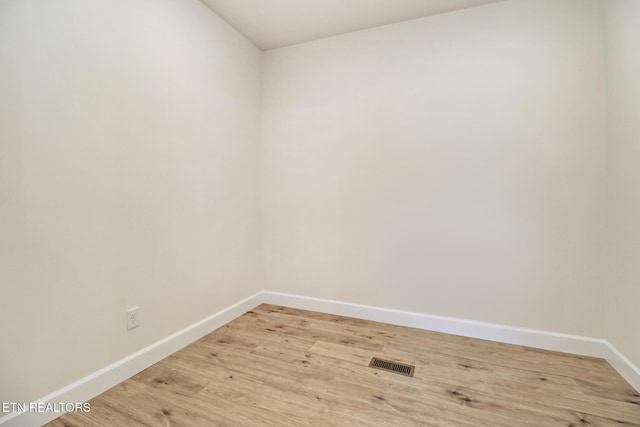 spare room featuring baseboards, light wood-style flooring, and visible vents