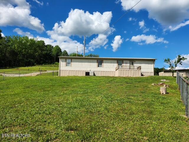 back of house featuring fence and a lawn