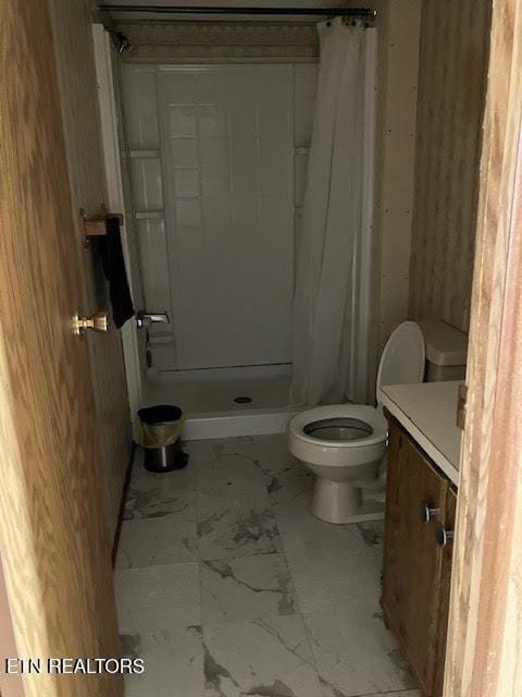 full bathroom featuring a stall shower, vanity, marble finish floor, and toilet