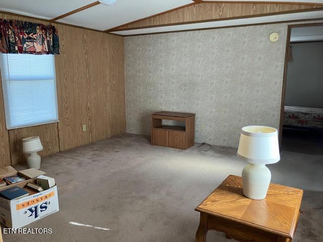 interior space featuring wooden walls, carpet, and lofted ceiling