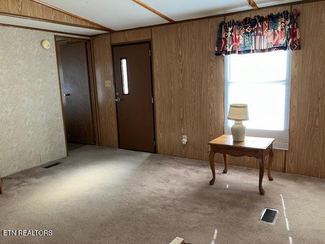 carpeted entryway featuring visible vents and wood walls