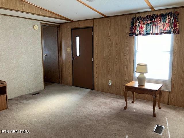foyer featuring wood walls, carpet flooring, and visible vents