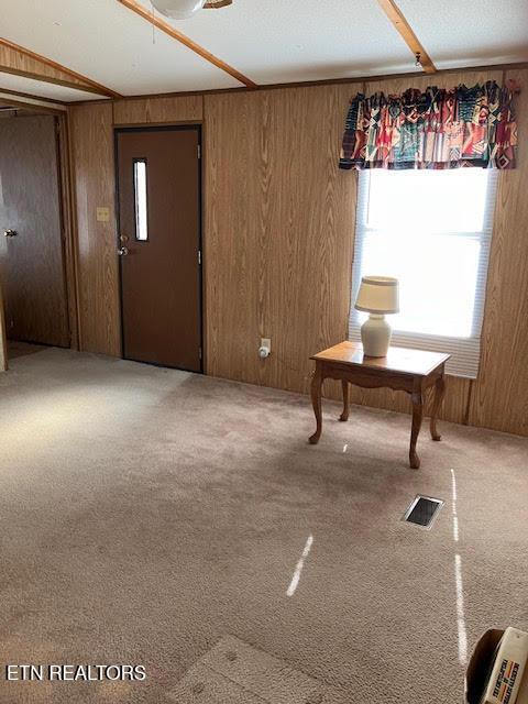 carpeted foyer featuring visible vents and wood walls