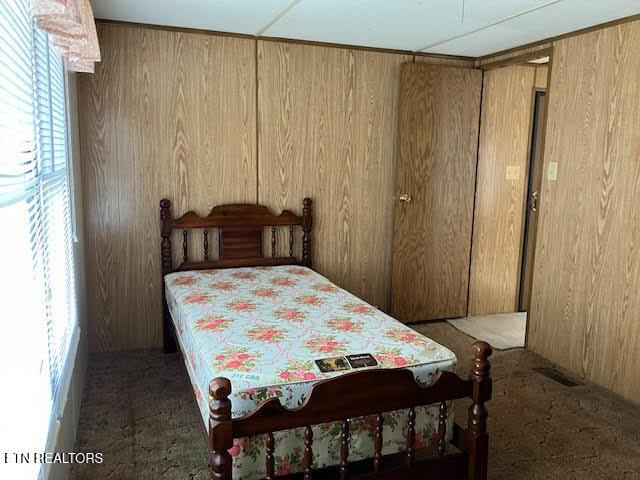 bedroom with wooden walls and carpet floors