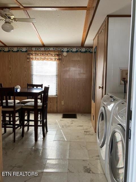 dining space with wooden walls, a ceiling fan, and washer and clothes dryer