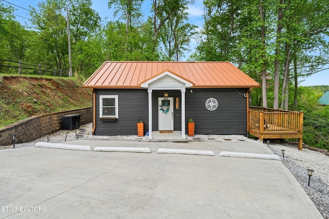view of front of property with cooling unit, a deck, metal roof, and a standing seam roof