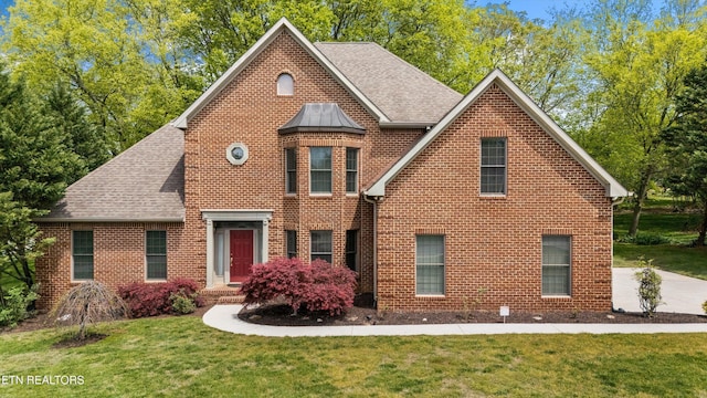 traditional-style home with a front lawn, brick siding, and a shingled roof