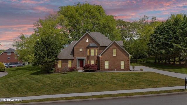traditional-style house with brick siding, driveway, and a front yard