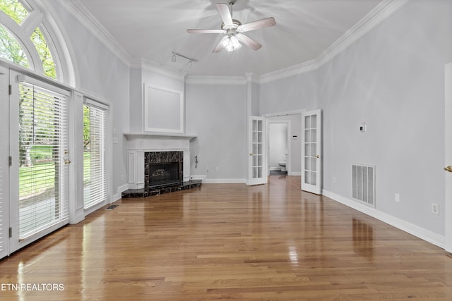 unfurnished living room featuring a high end fireplace, track lighting, ceiling fan, french doors, and visible vents